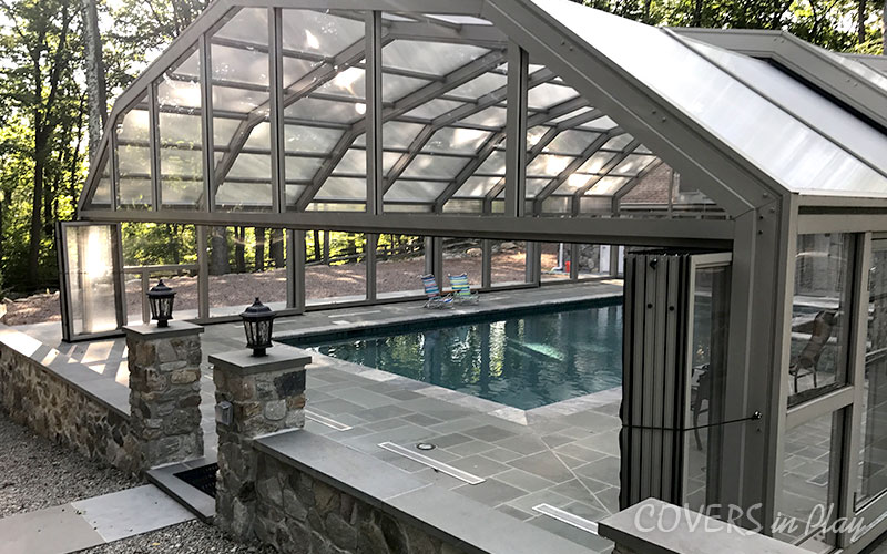 Side angled exterior view of closed residential pool enclosure with opened bifold doors in Kinnelon