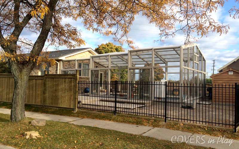 Exterior side view of a closed pool enclosure in residential backyard in Burlington