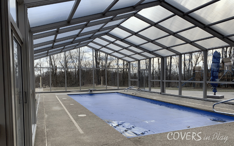 Interior view of backyard pool enclosure surrounded by trees in Triadelphia, WV