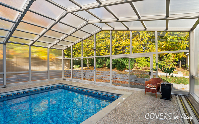 Interior view of closed pool enclosure with frosted windows and trees surrounding the infrastructure